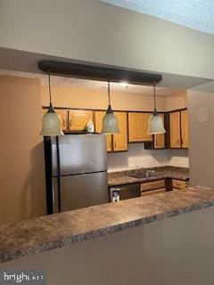 kitchen with kitchen peninsula, sink, dishwasher, stainless steel refrigerator, and hanging light fixtures