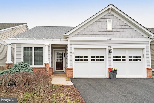 view of front of home with driveway, a shingled roof, and a garage