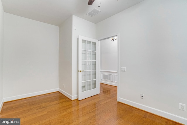 spare room featuring ceiling fan, visible vents, baseboards, and wood finished floors