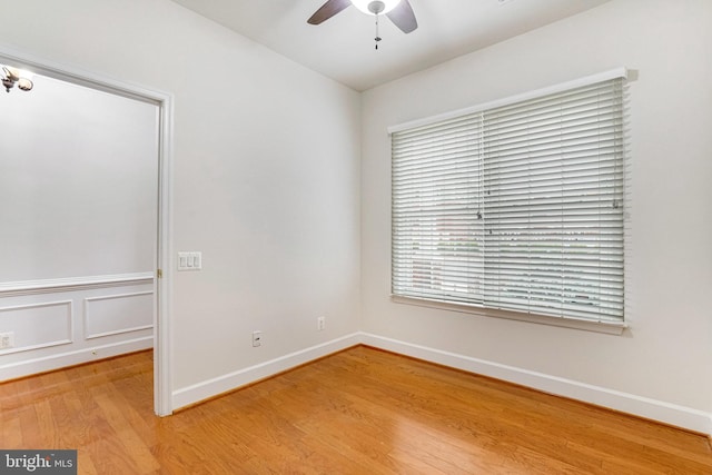 spare room featuring a ceiling fan, light wood-type flooring, and baseboards