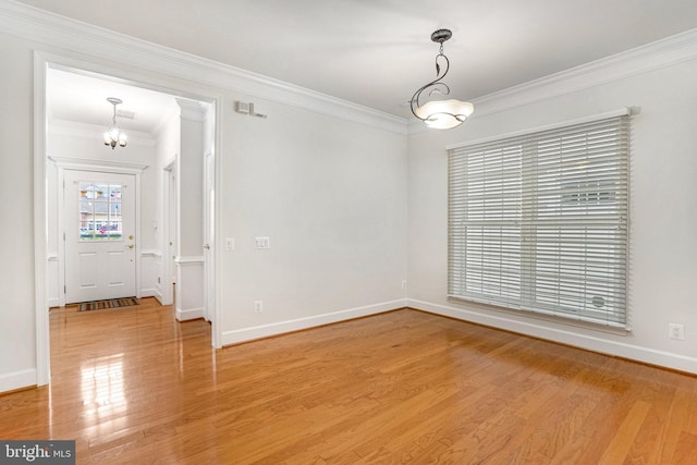 spare room featuring crown molding, baseboards, light wood finished floors, and a chandelier