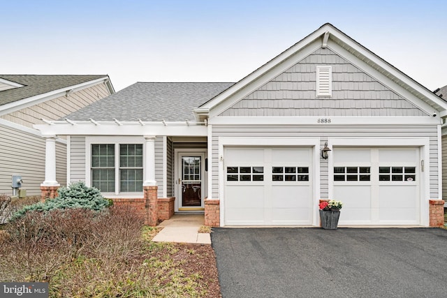 view of front of home with brick siding, a garage, driveway, and a shingled roof