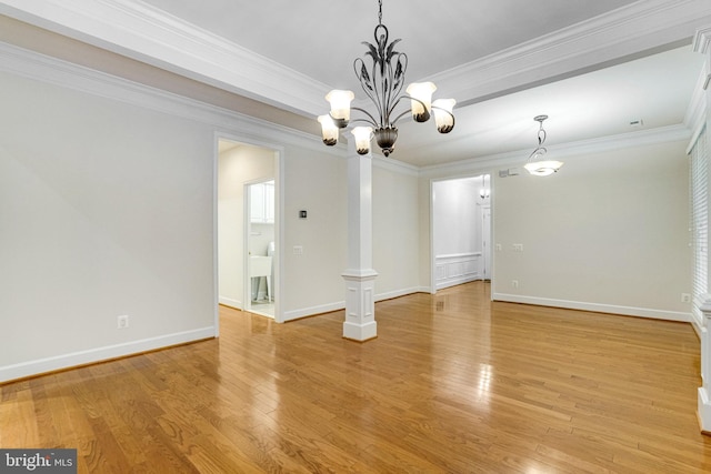 empty room featuring a notable chandelier, light wood-type flooring, baseboards, and ornamental molding