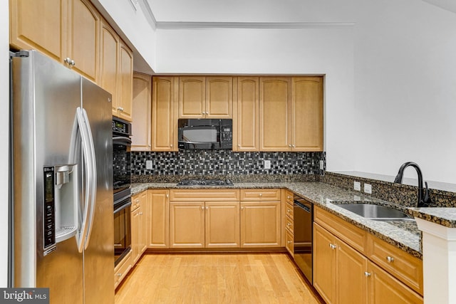 kitchen with light wood-type flooring, decorative backsplash, black appliances, and dark stone counters