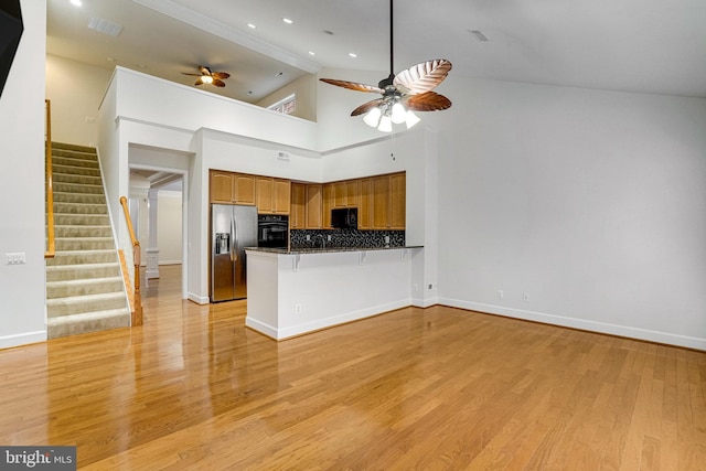 kitchen featuring light wood-type flooring, a peninsula, black appliances, and ceiling fan