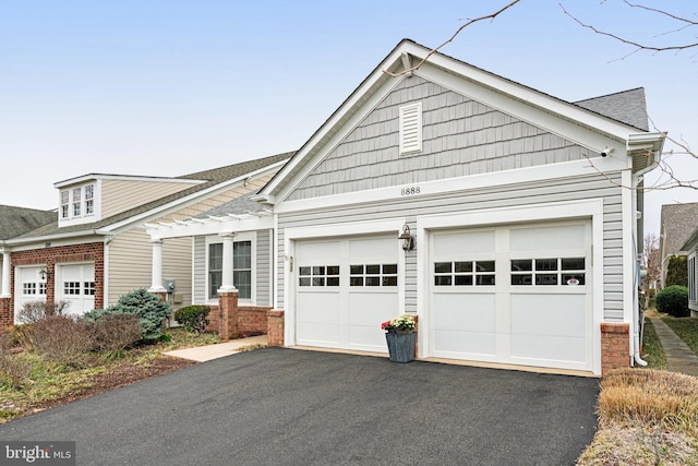 view of front facade with aphalt driveway, an attached garage, a shingled roof, and brick siding