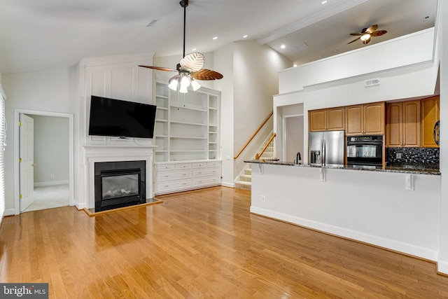 kitchen featuring brown cabinetry, light wood-style flooring, a ceiling fan, and stainless steel refrigerator with ice dispenser