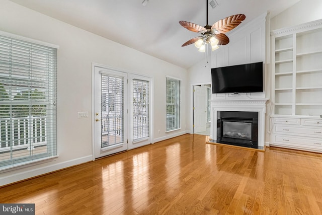 unfurnished living room with a glass covered fireplace, a healthy amount of sunlight, wood finished floors, and ceiling fan