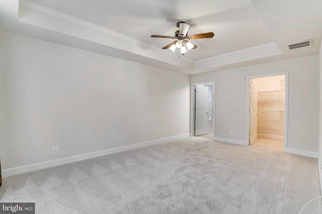 unfurnished bedroom with visible vents, ornamental molding, baseboards, a raised ceiling, and light colored carpet