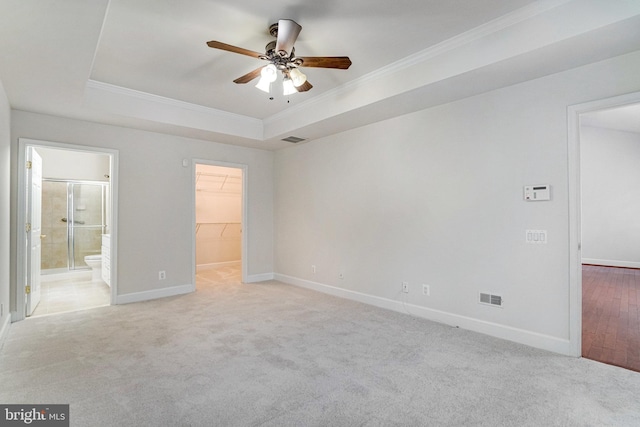 unfurnished bedroom with visible vents, a raised ceiling, and light carpet