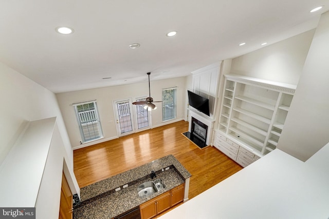 living area with light wood-style flooring, a fireplace with flush hearth, a ceiling fan, and recessed lighting