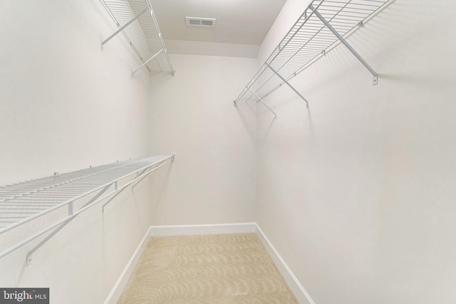 walk in closet with visible vents and light colored carpet