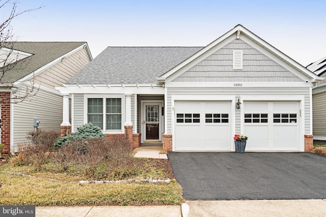 craftsman inspired home with brick siding, driveway, a shingled roof, and a garage