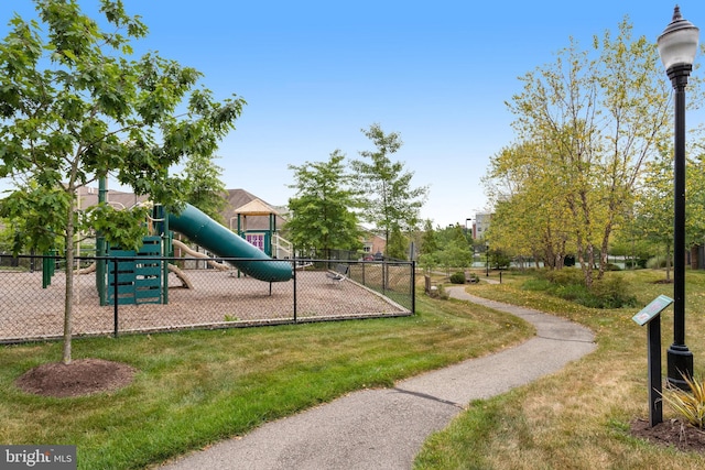 community playground featuring a yard and fence