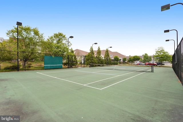 view of tennis court with community basketball court and fence