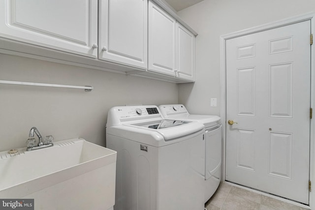 clothes washing area with a sink, cabinet space, and washing machine and clothes dryer