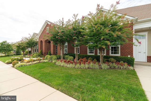 view of front of property featuring brick siding and a front yard