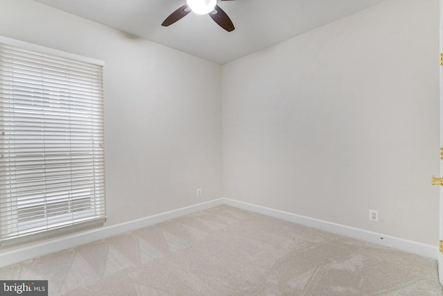 spare room with baseboards, light colored carpet, and a ceiling fan