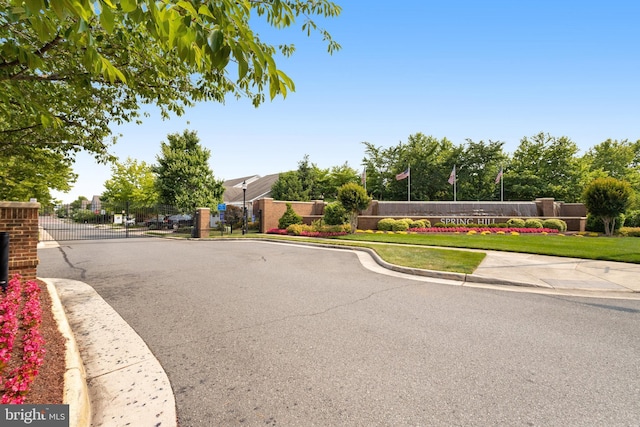 view of road featuring a gate, curbs, sidewalks, and a gated entry