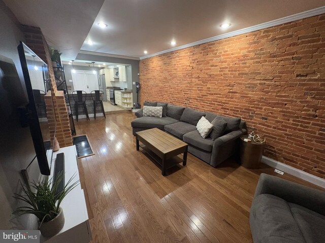 living room featuring crown molding, brick wall, and wood-type flooring