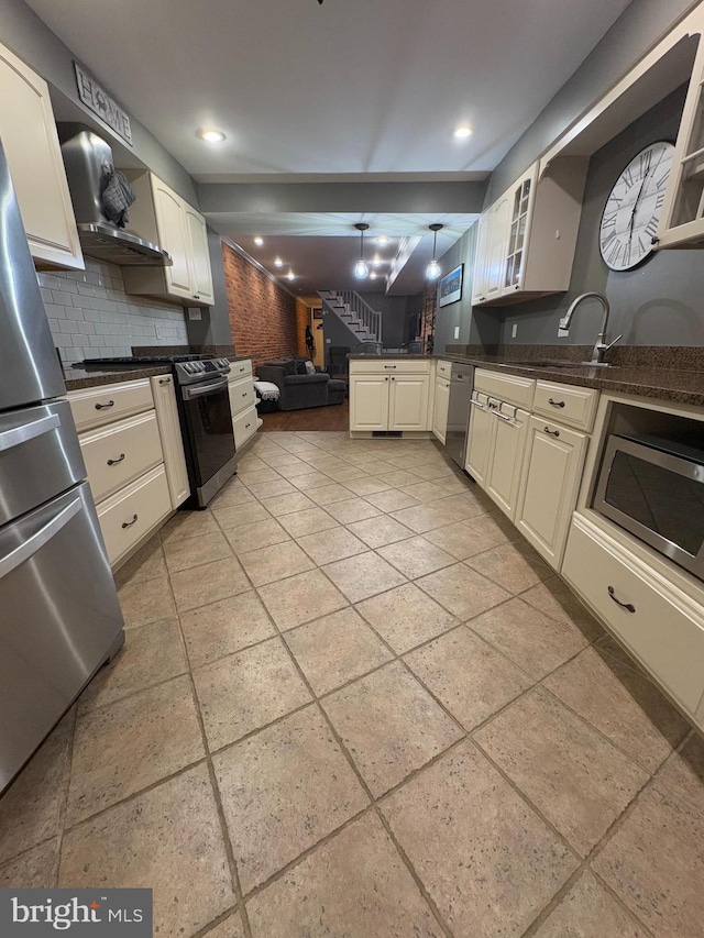 kitchen featuring decorative backsplash, appliances with stainless steel finishes, hanging light fixtures, and sink