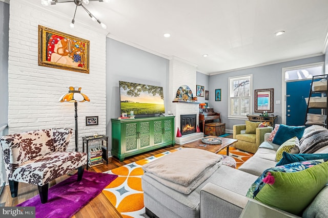 living room featuring a fireplace, wood-type flooring, a chandelier, and crown molding