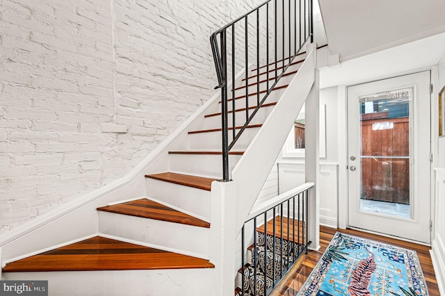 stairway featuring hardwood / wood-style flooring and brick wall