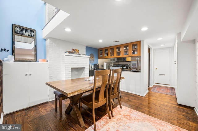 dining room with hardwood / wood-style floors and a brick fireplace