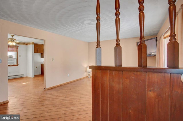 interior space featuring a baseboard heating unit, ceiling fan, and light hardwood / wood-style floors