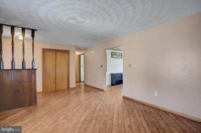 unfurnished room featuring a textured ceiling and light hardwood / wood-style flooring