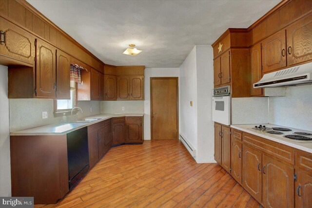 kitchen featuring white appliances, light hardwood / wood-style flooring, tasteful backsplash, baseboard heating, and sink