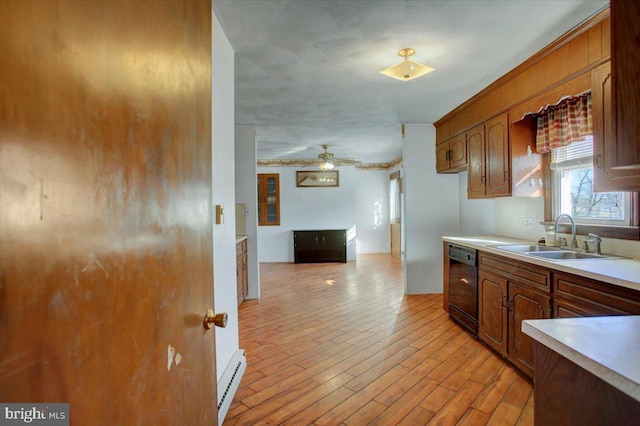 kitchen with dishwasher, baseboard heating, light wood-type flooring, ceiling fan, and sink