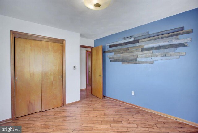 unfurnished bedroom with light wood-type flooring and a closet