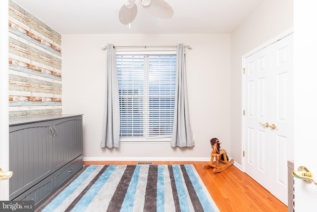 unfurnished bedroom featuring wood-type flooring, ceiling fan, and wood walls