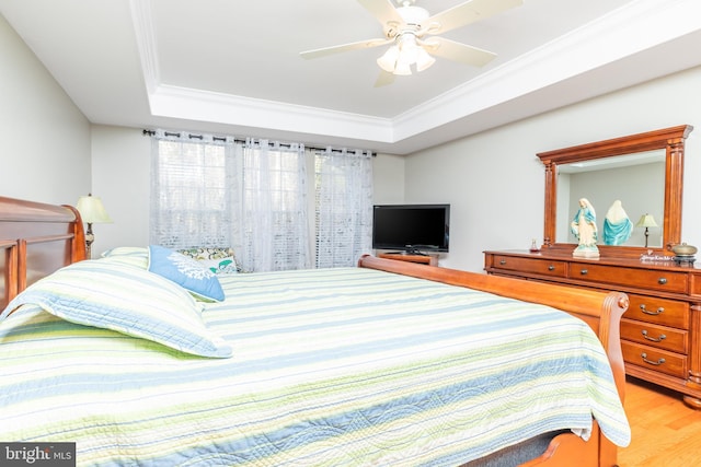 bedroom featuring ceiling fan, ornamental molding, a tray ceiling, and hardwood / wood-style floors