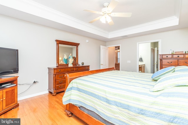 bedroom with ensuite bathroom, crown molding, a raised ceiling, and light wood-type flooring