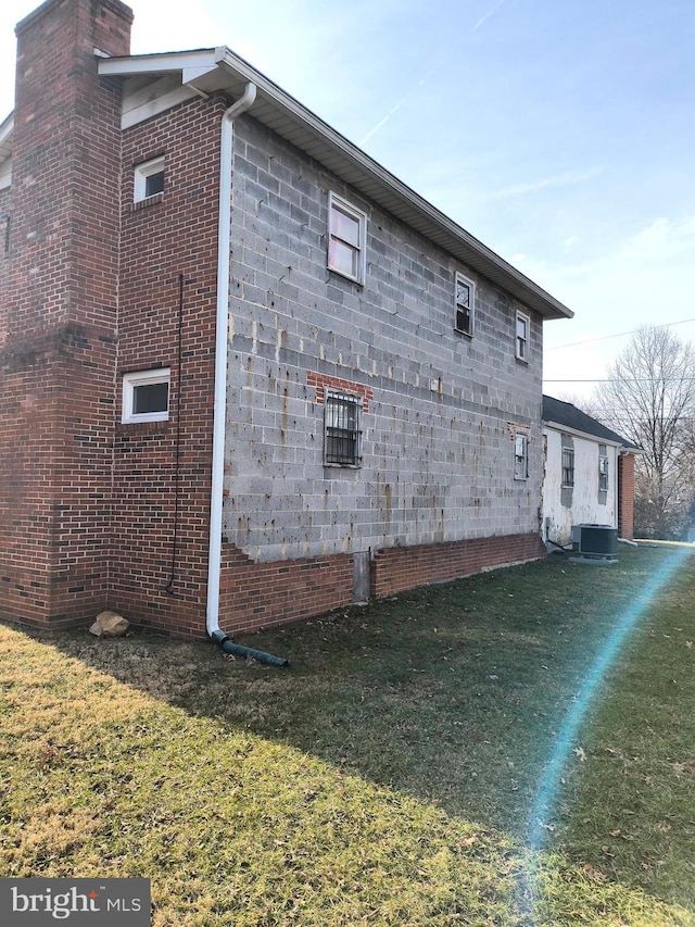 view of side of home featuring central AC unit and a lawn