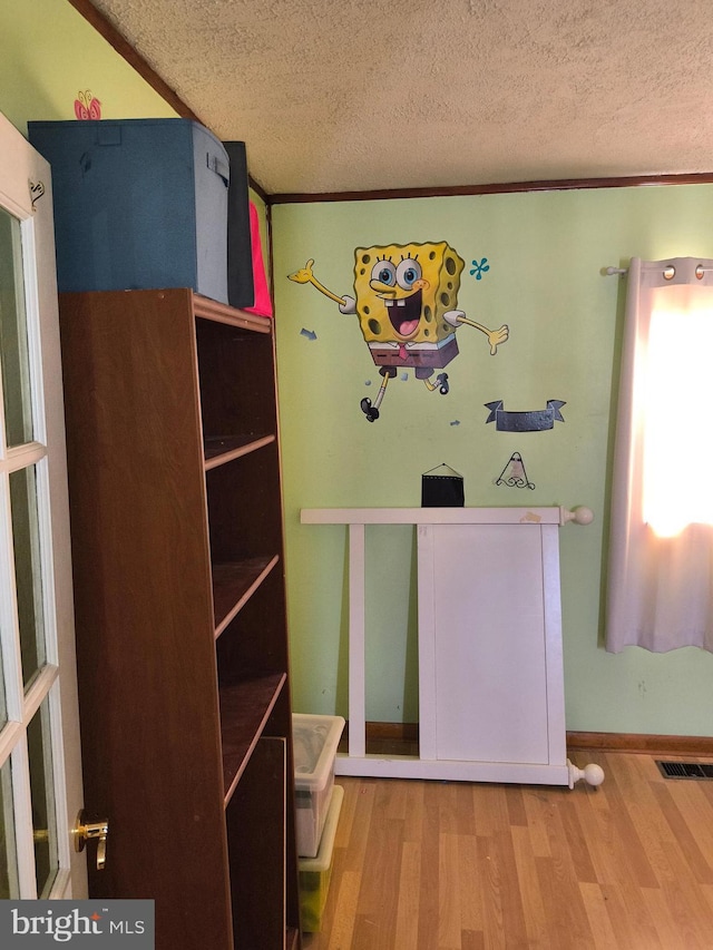 unfurnished bedroom featuring ornamental molding, hardwood / wood-style floors, and a textured ceiling