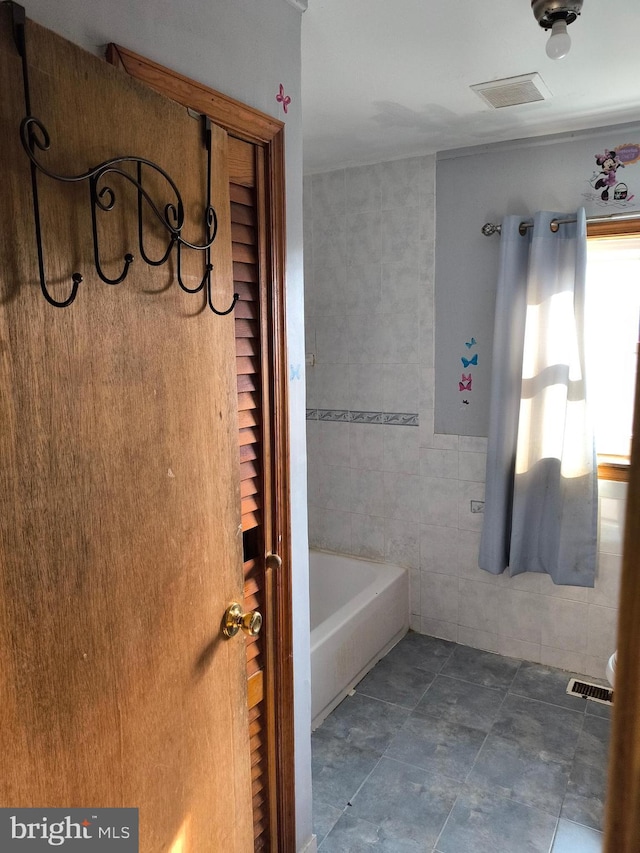 bathroom with tile walls and a tub to relax in