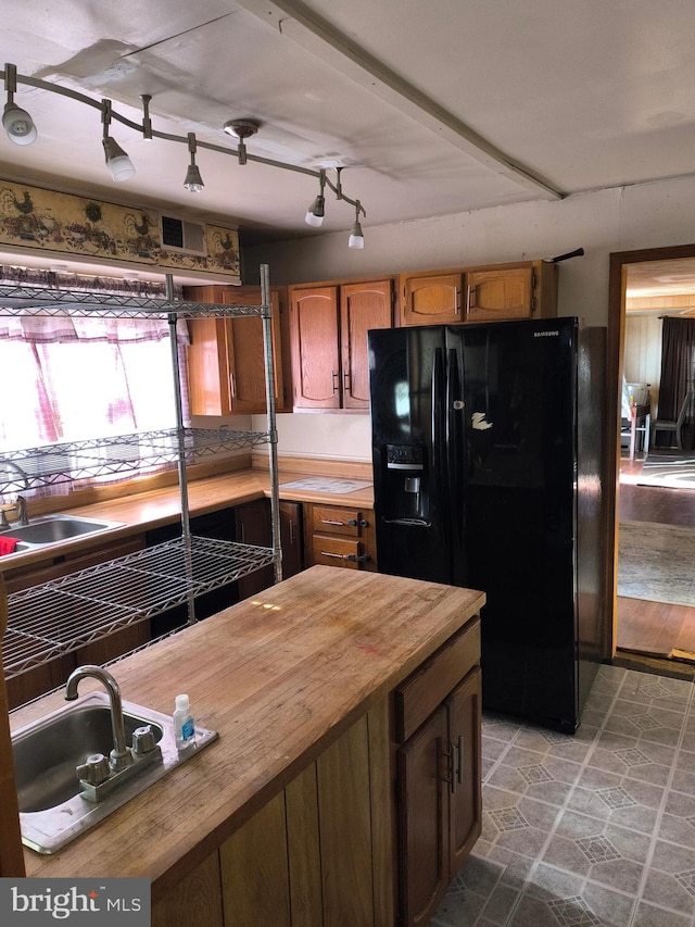 kitchen featuring black fridge, wooden counters, rail lighting, and sink