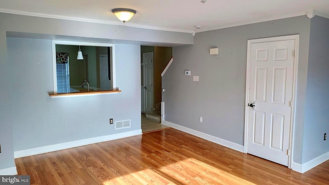 unfurnished room featuring hardwood / wood-style floors, ornamental molding, and sink