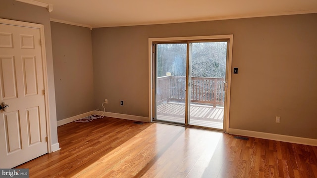 empty room with crown molding and light hardwood / wood-style floors