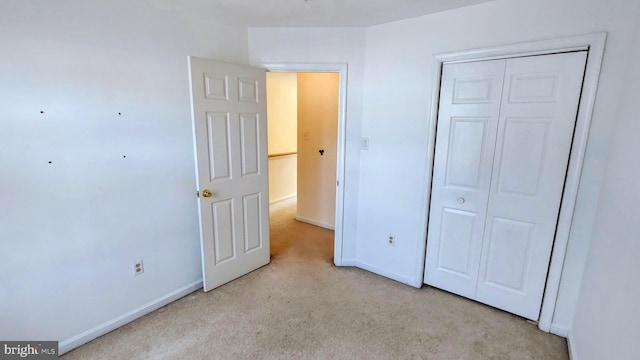 unfurnished bedroom featuring light colored carpet and a closet