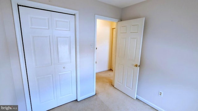 unfurnished bedroom with light carpet and a closet