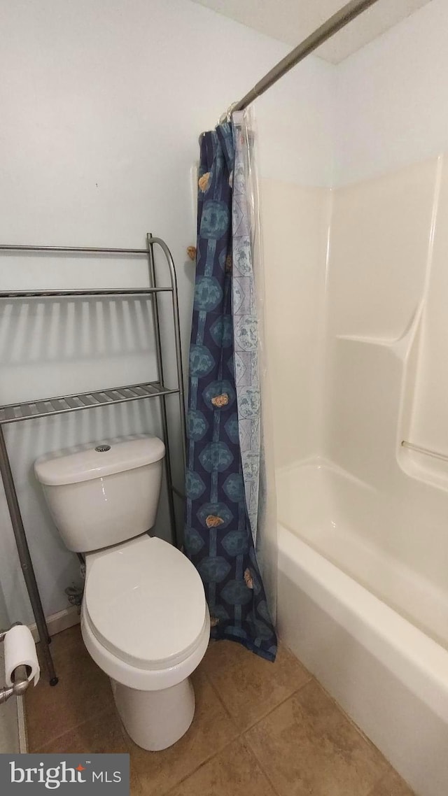 bathroom with tile patterned floors, toilet, and shower / bath combo with shower curtain