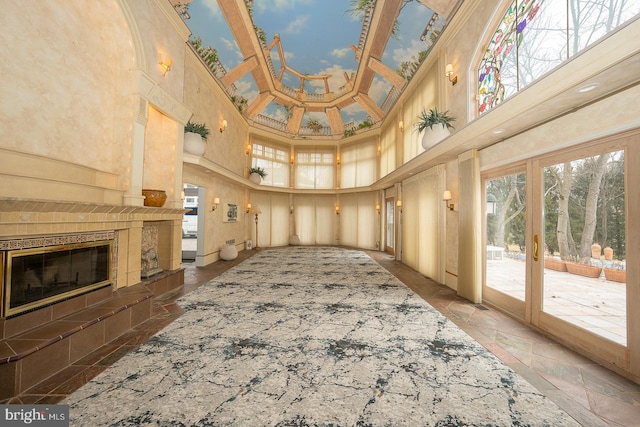 living room with stone tile floors, a high ceiling, and a fireplace