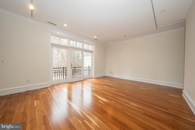 spare room with baseboards, ornamental molding, and wood finished floors