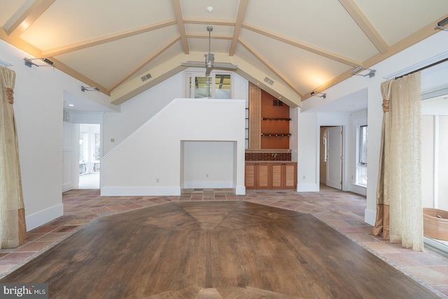 unfurnished living room featuring stone finish flooring, beam ceiling, visible vents, and baseboards