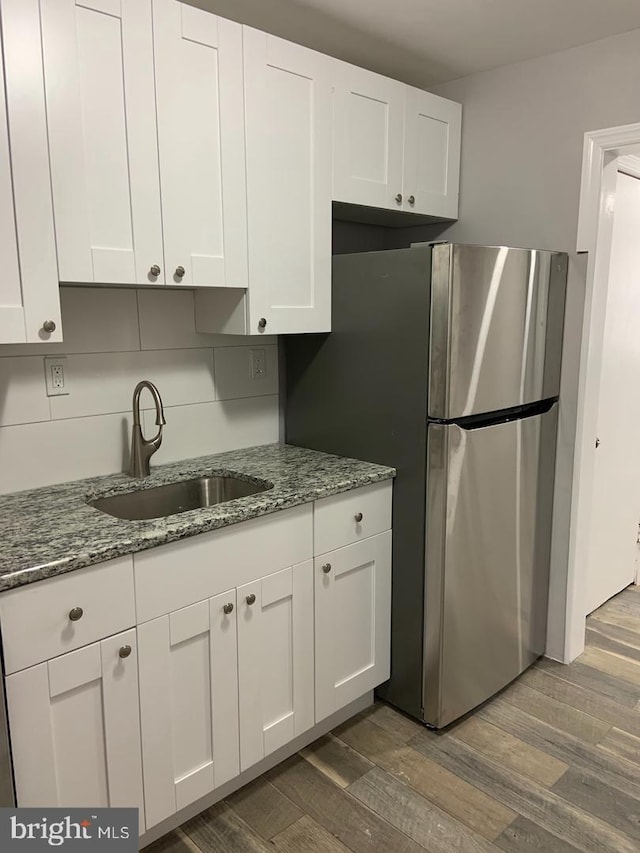 kitchen featuring white cabinetry, sink, wood-type flooring, and stone countertops