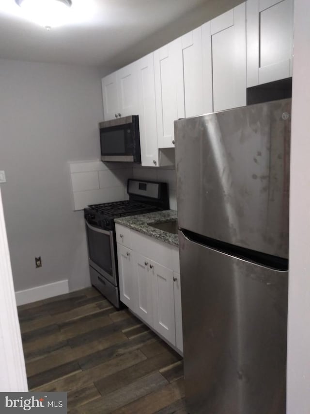 kitchen featuring decorative backsplash, dark hardwood / wood-style flooring, dark stone counters, stainless steel appliances, and white cabinetry